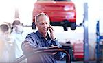 Man talking on cell phone in auto repair shop