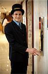 Profile shot of a doorman in a bowler hat waiting near the elevators