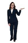 Woman in business attire posing with an open palm, copy space concept.