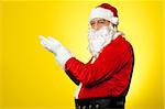 Side profile of Santa facing camera with open palms. All on yellow background.