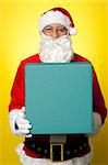 Isolated smiling Santa holding gift box and looking at camera.