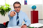 Bespectacled male boss pointing at you. Business concept