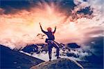 Man standing on the stone with hands up. Trekking in Nepal