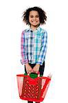 Smiling happy small girl holding red basket and carrying various stationery in it