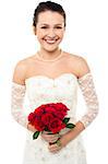 Gorgeous young bride holding a rose bouquet smiling at the camera