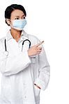 Young female physician wearing face mask, pointing at something