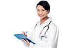 Smiling female physician writing prescription on clipboard