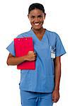 Charming young african nurse posing with red clipboard, medical uniform.
