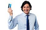 Smiling young corporate man holding up his credit card