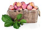 Fresh plums in wooden basket with green leaves. Isolated on white background