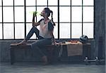 Fit woman in profile sitting on bench in loft gym drinking water. After a good workout, it's important to hydrate.