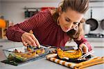 An elegant woman in a kitchen focuses on serving a slice of roasted pumpkin onto a dark plate.