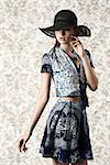 very pretty woman in sensual pose wearing black hat and blue summer printed top and skirt