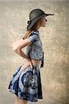 fashion portrait of pretty girl turned on profile with black hat and lovely blue spring outfit