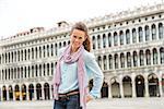 Smiling happily, a woman tourist relaxes, enjoying the feeling of being on Venice's St. Mark's Square.