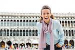 This is what a happy tourist looks like, friends. Here, an elegant, happy woman laughs at the camera, leaning down happily, while her hands are in her pockets.