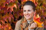 Portrait of pensive young woman with leafs in front of autumn foliage