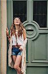 Portrait of happy young woman wearing boho clothes standing outside buildings in street