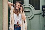 Happy woman wearing bohemian style clothes standing outside buildings in street and talking cell phone