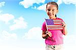 Little girl with american flag against blue sky