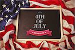 Independence day graphic against american flag on chalkboard