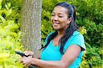 Mature woman pruning hedge in garden