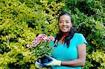 Portrait of mature woman with flowering pot plant in garden