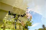 Senior man at home, using telescope through window