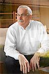 Senior man at home, sitting in chair, looking away