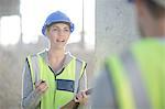 Female surveyor with clipboard talking to builder on construction site