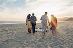 Two young couples walking along beach, rear view