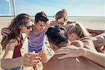 Group of friends in huddle on beach