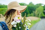 Portrait of young woman with bunch of flowers and wearing straw hat