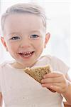 Portrait of a smiling young boy eating a sandwich.