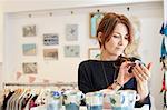 A mature woman in a gift shop holding a small china cup in her hands.