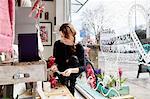 A mature woman in a gift shop by the window, holding a small star.