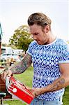 Man with tattoos looking at a red vintage radio at a flea market.