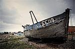 Abandoned wooden boat lying on a shingle beach.