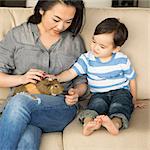 Smiling woman sitting on a sofa, a guinea pig sitting on her lap, her young son stroking the animal.