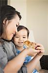 Smiling woman holding a tiny chick in her hands, her young son watching.