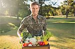 Smiling man carrying box of vegetables