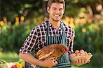 Happy farmer holding chicken and egg