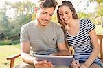 Cute couple sitting on the bench and using tablet