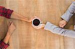Two hands holding a cup of coffee on wooden table