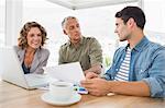 Creative business people using laptop in meeting