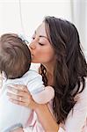 Cheerful mother kissing her baby girl