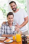 Happy homosexual couple looking at camera during breakfast