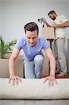 Handsome man unrolling carpet with his behind