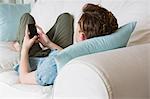 Rear view of young man using his smartphone on couch