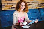 Portrait of an happy woman using a tablet and taking a coffee